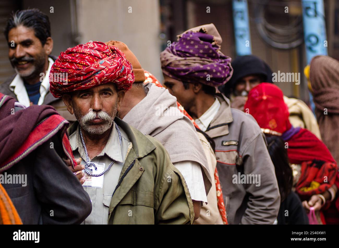 Gli anziani in abbigliamento tradizionale si riuniscono per l'osservanza spirituale durante una vivace festa religiosa in India Foto Stock