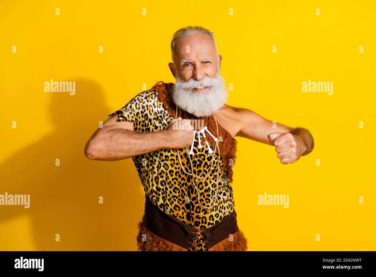 Foto di divertente e forte grotta indossano la pelle leoprad che batte pugni petto spazio emtpy sfondo giallo isolato Foto Stock