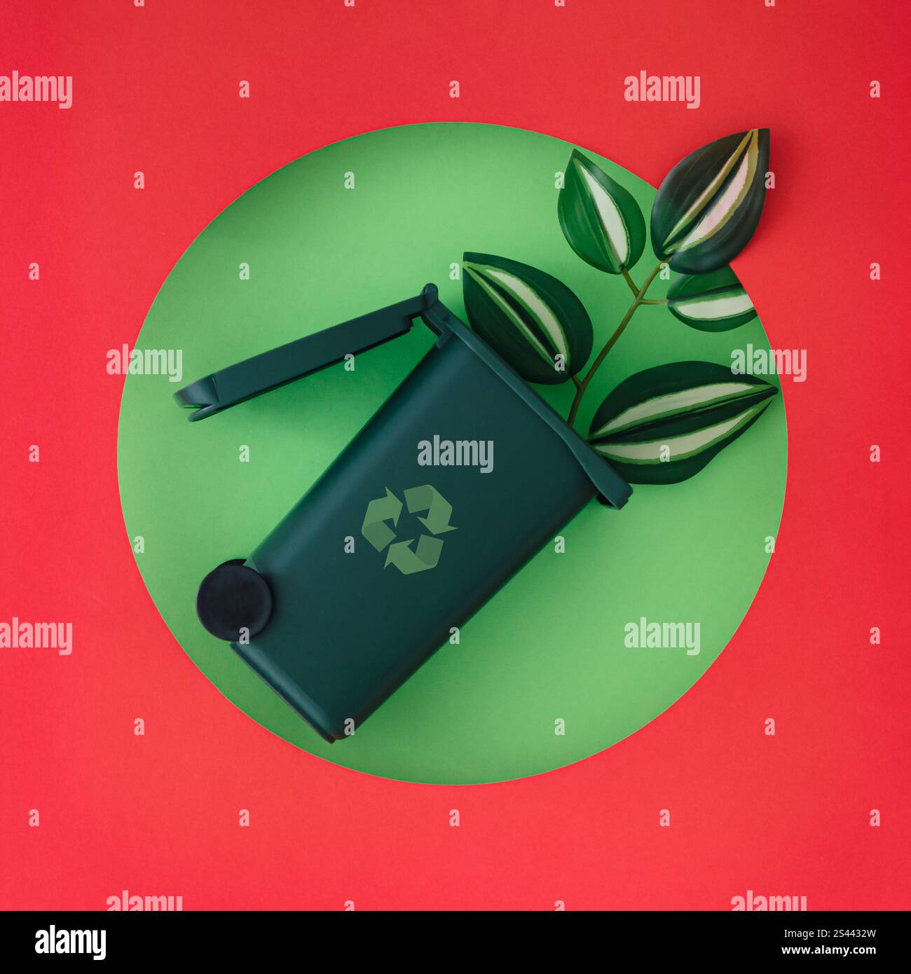 Layout ecologico creativo con cestino e foglie visibili attraverso un'apertura circolare su sfondo verde. Contenitore per lo smaltimento dei rifiuti. Foto Stock