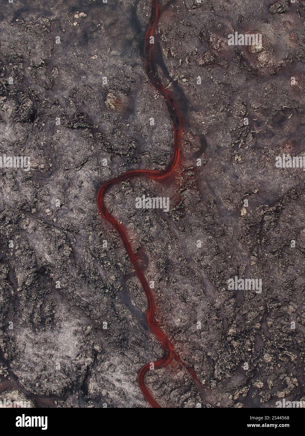 Vista aerea di una tortuosa strada rossa ricca di ferro, che attraversa aspri terreni vulcanici in Islanda, mostrando colori e motivi naturali unici. Foto Stock