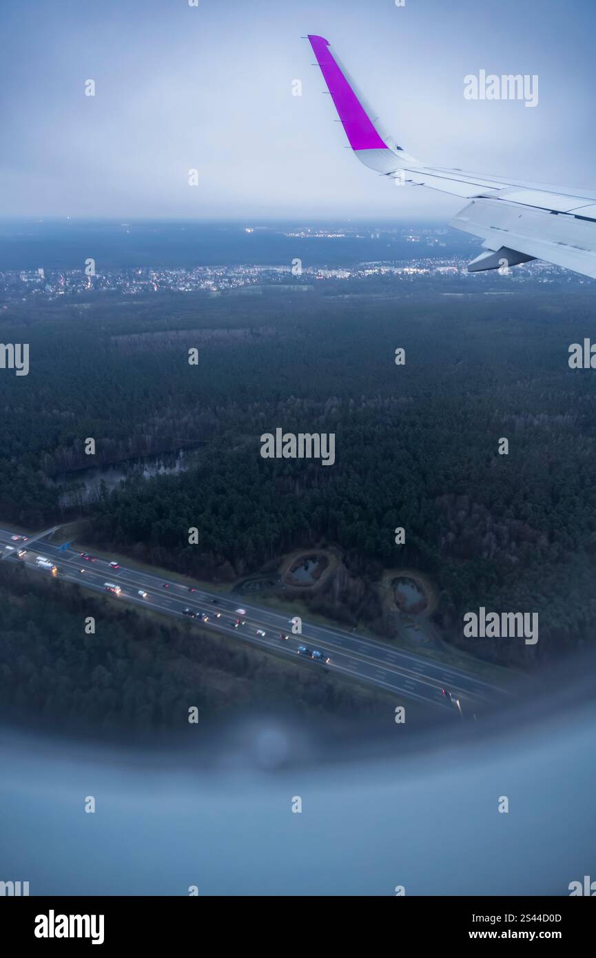 Vista di una città attraverso l'oblò di un aereo mentre si prepara ad atterrare, in una mattina d'inverno presto. Foto Stock