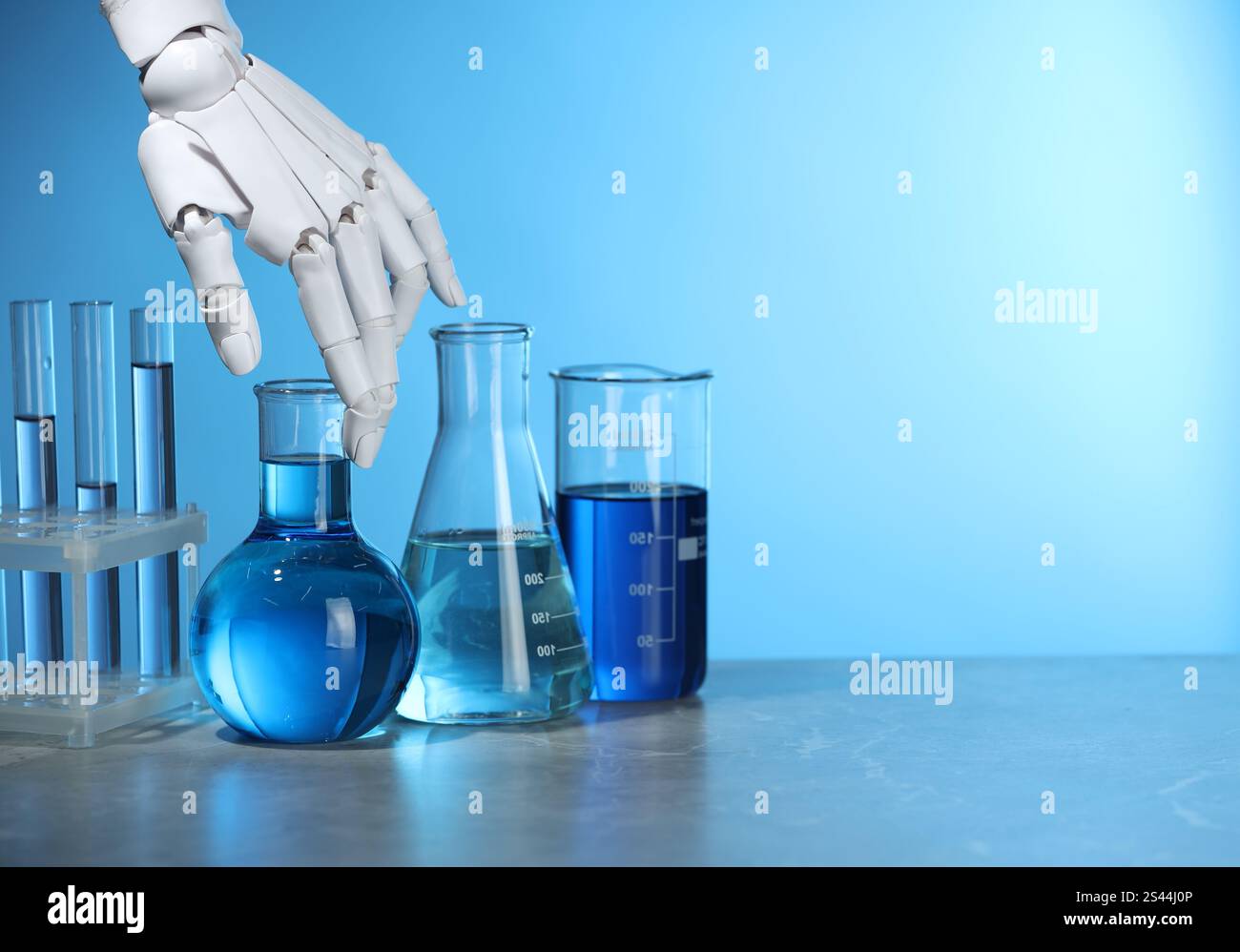 Intelligenza artificiale. Vetreria robot per mani e laboratorio con liquidi sul tavolo su sfondo azzurro, spazio per testo Foto Stock