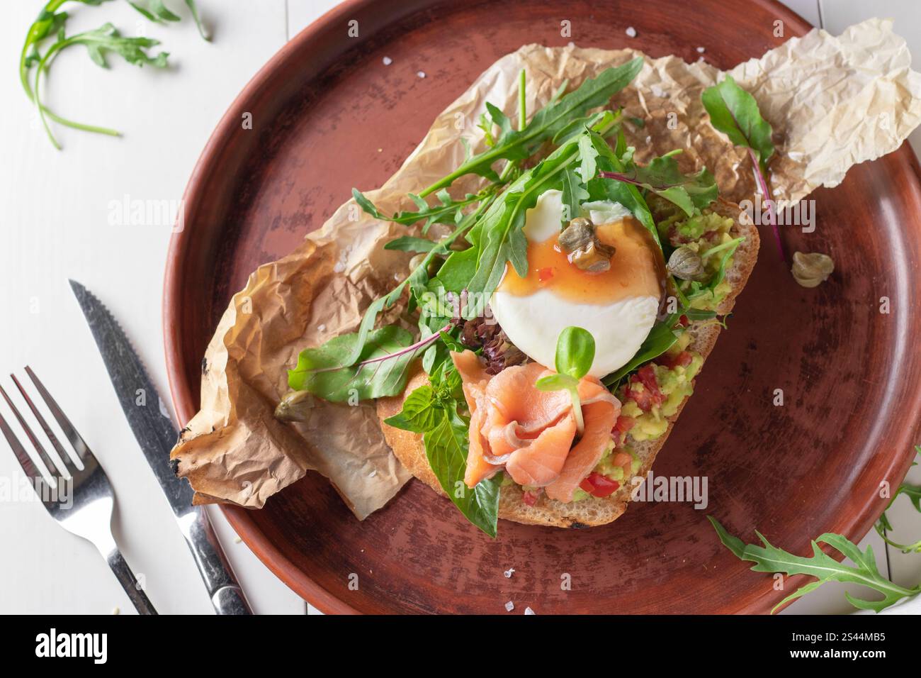 Bruschetta con avocado, salmone salato, microgreen e uova in camicia, vista dall'alto Foto Stock
