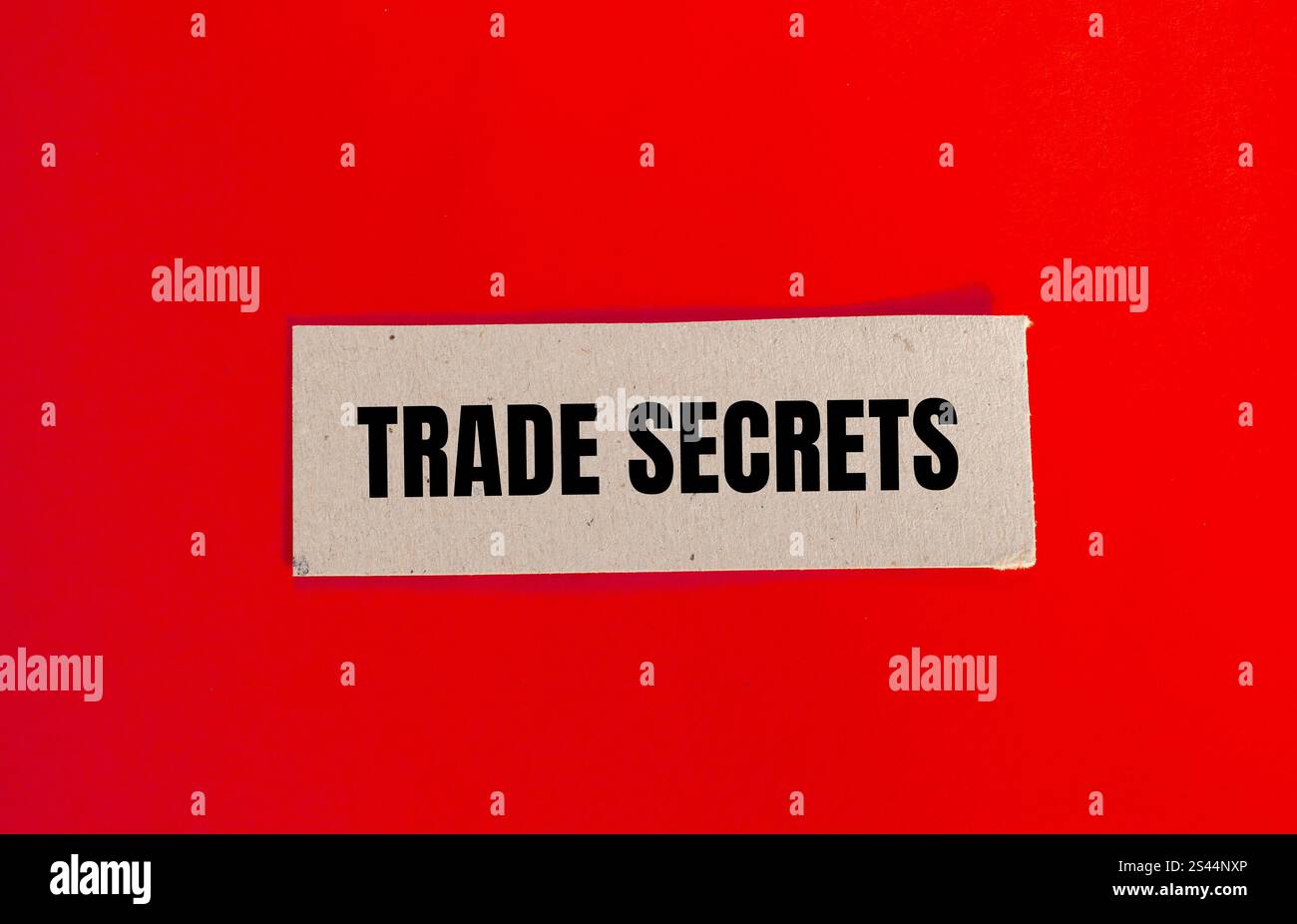 Messaggio segreto commerciale scritto su carta con sfondo rosso. Simbolo dei segreti commerciali concettuali. Copia spazio. Foto Stock