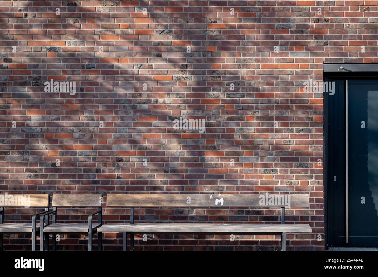 Una panchina all'ombra di fronte a un muro di mattoni Foto Stock