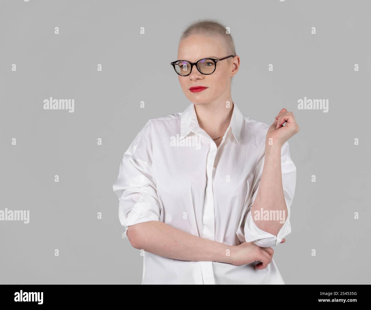 Ritratto di una bella giovane donna caucasica con la testa rasata. Sopravvissuta al cancro femminile. Sorridere con gli occhiali in posa in modo sicuro in uno Studio. Un portrai Foto Stock