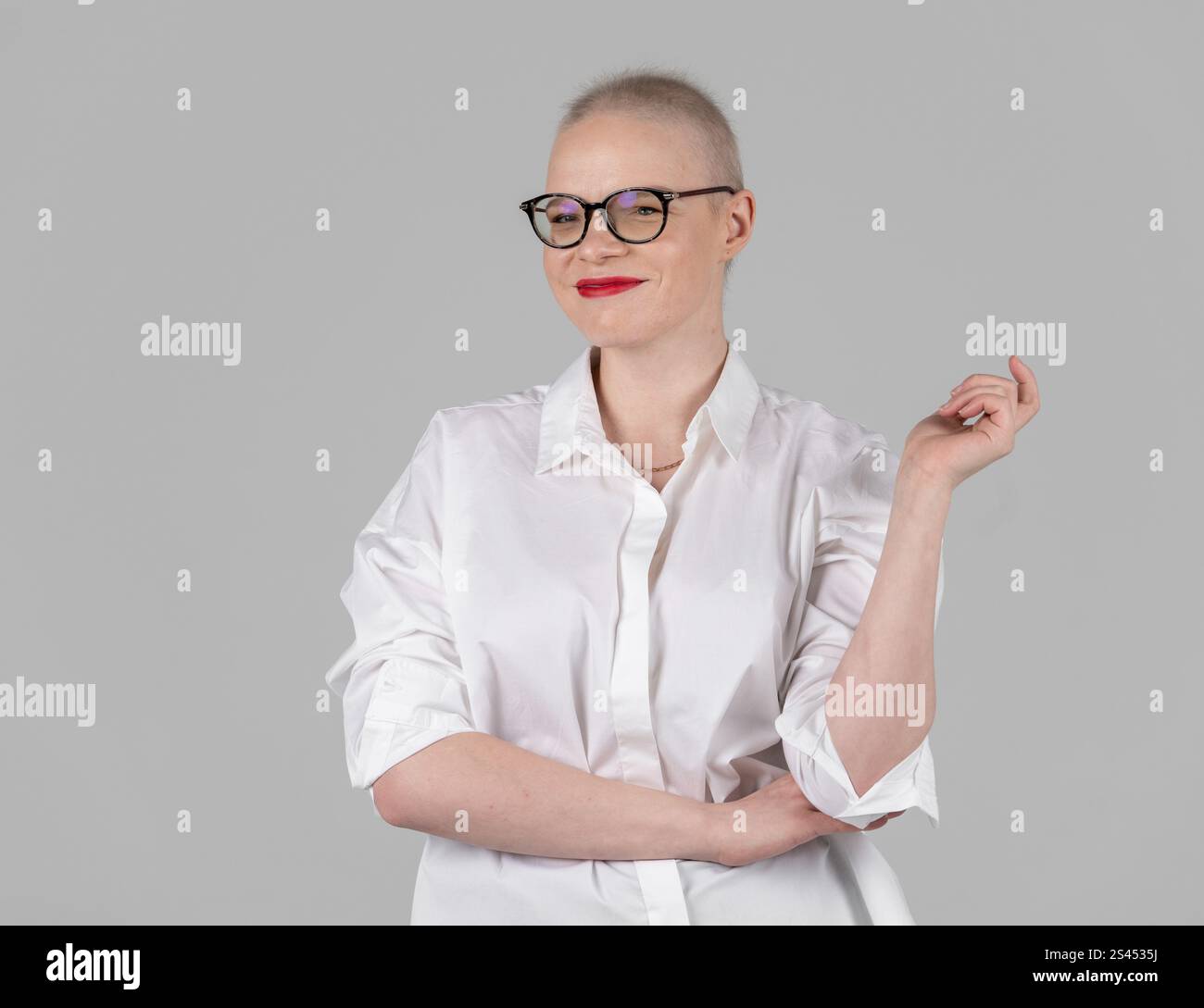 Ritratto di una bella giovane donna caucasica con la testa rasata. Sopravvissuta al cancro femminile. Sorridere con gli occhiali in posa in modo sicuro in uno Studio. Un portrai Foto Stock