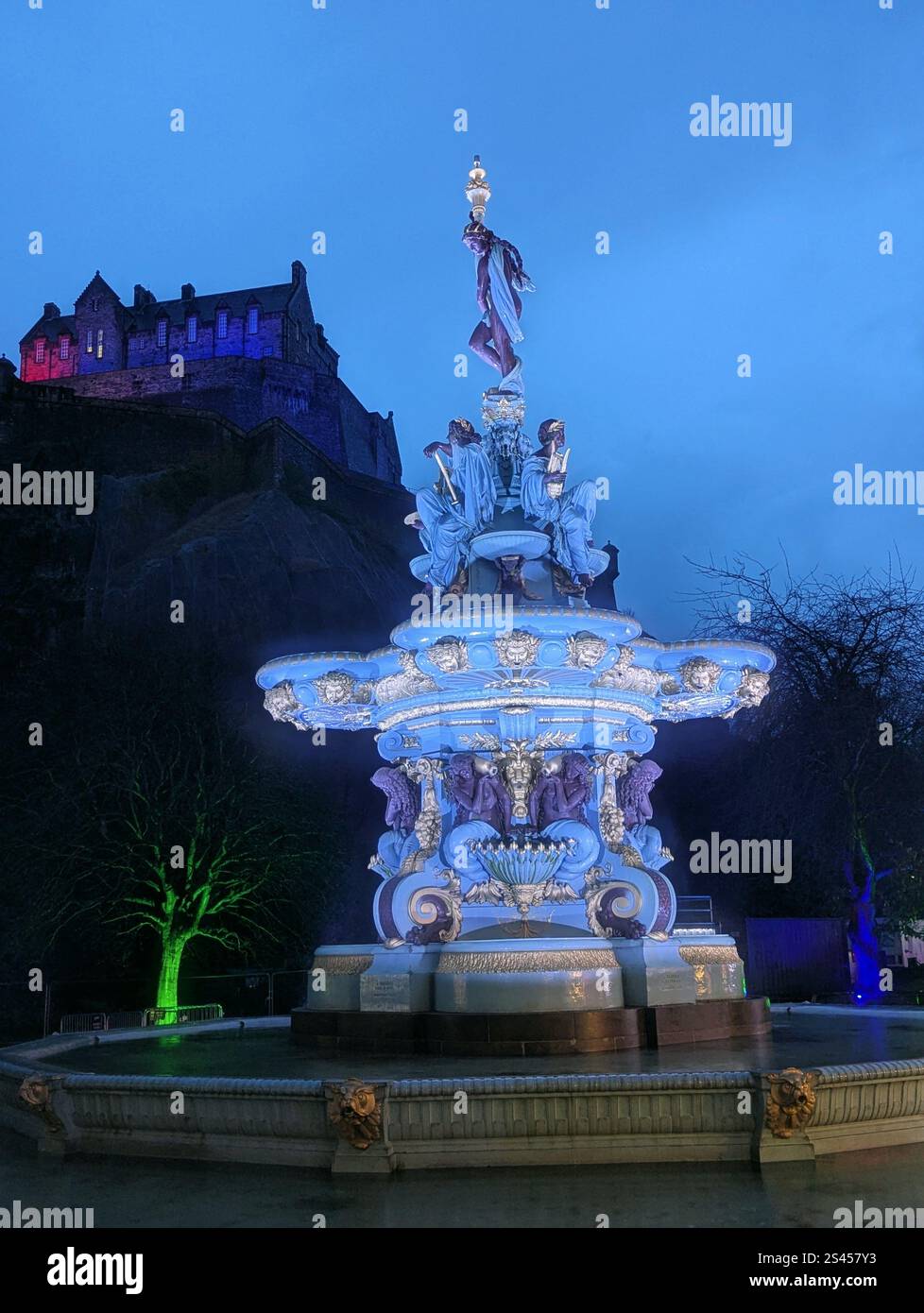 Ross Fountain illuminata di notte, con il Castello di Edimburgo che si illumina sullo sfondo, mescolando storia e bellezza nel cuore della Scozia - Immagine stock catturata con smartphone