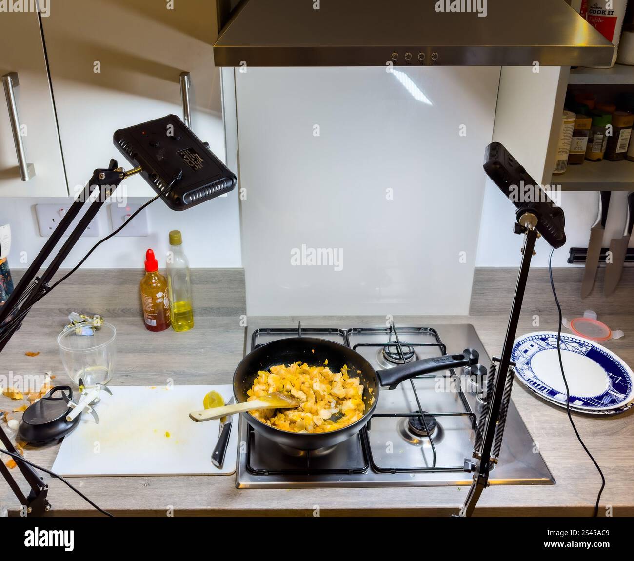 la fotografia illumina il cibo fotografando il curry di pollo fatto in casa, cucinato in una teglia nera su un piano cottura con un cucchiaio di legno che mescola la salsa Foto Stock