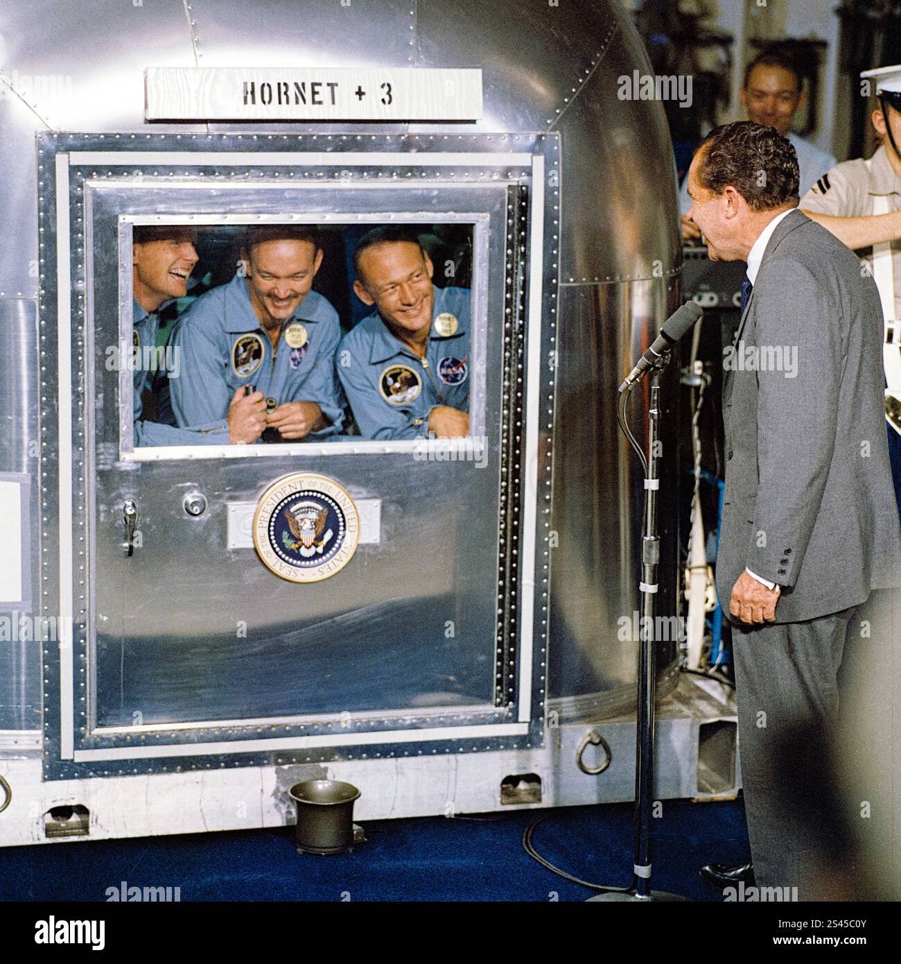 Il presidente degli Stati Uniti Richard Nixon (1913-1994) saluta gli astronauti dell'Apollo 11 Neil Armstrong, Buzz Aldrin e Michael Collins il 24 luglio 1969 attraverso la finestra del loro Mobile Quarantine Facility (MQF) a bordo della USS Hornet dopo il loro atterraggio sulla luna e ritorno sulla Terra. Foto Stock