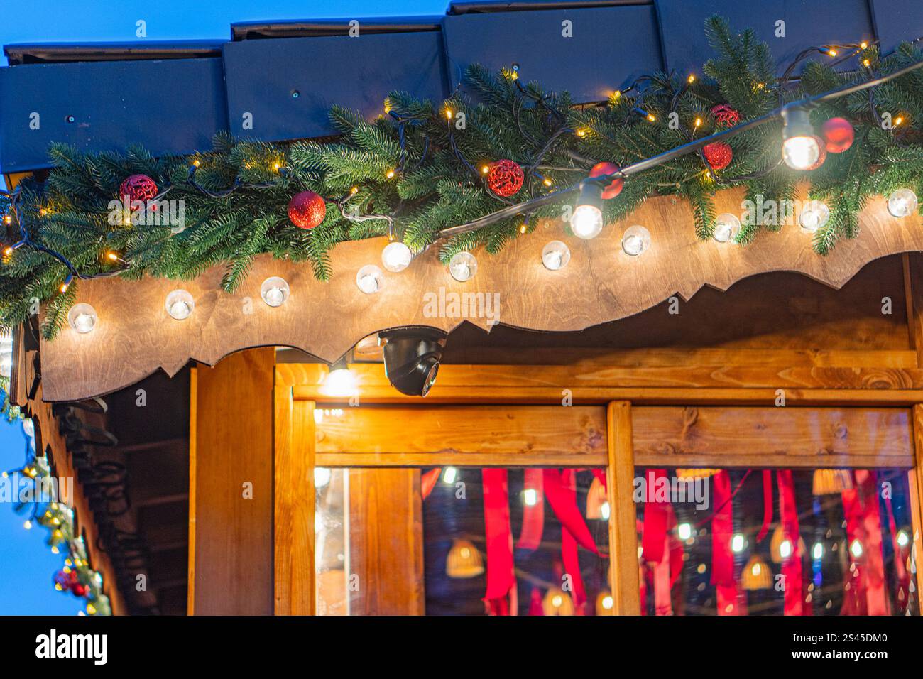 Scena notturna all'aperto con atmosfera festosa, struttura in legno decorata per le festività natalizie, illuminata da ghirlande e luci, festeggiamenti natalizi Foto Stock