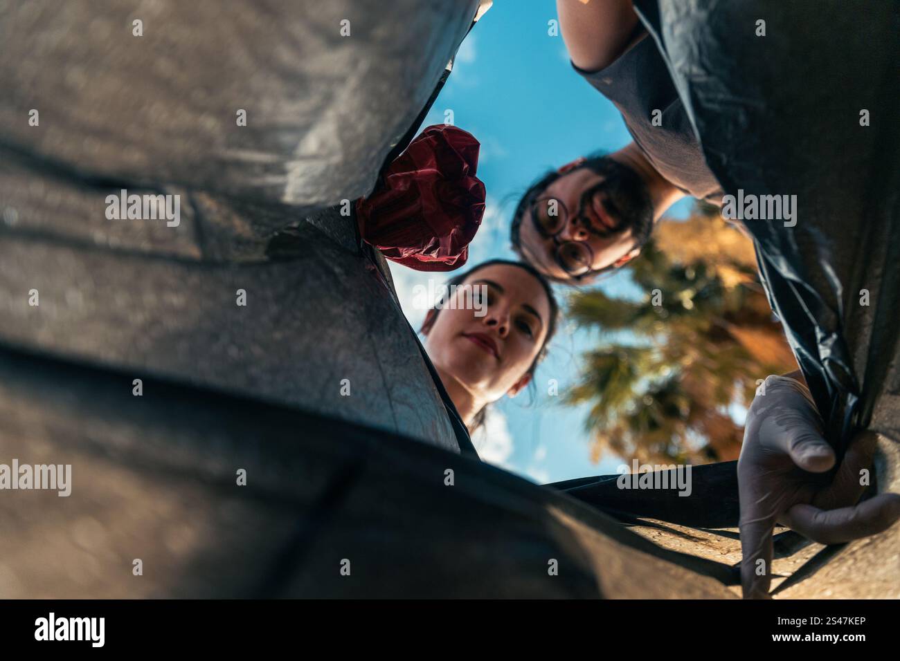 Un uomo e una donna stanno gettando la spazzatura in un sacco della spazzatura. Foto Stock