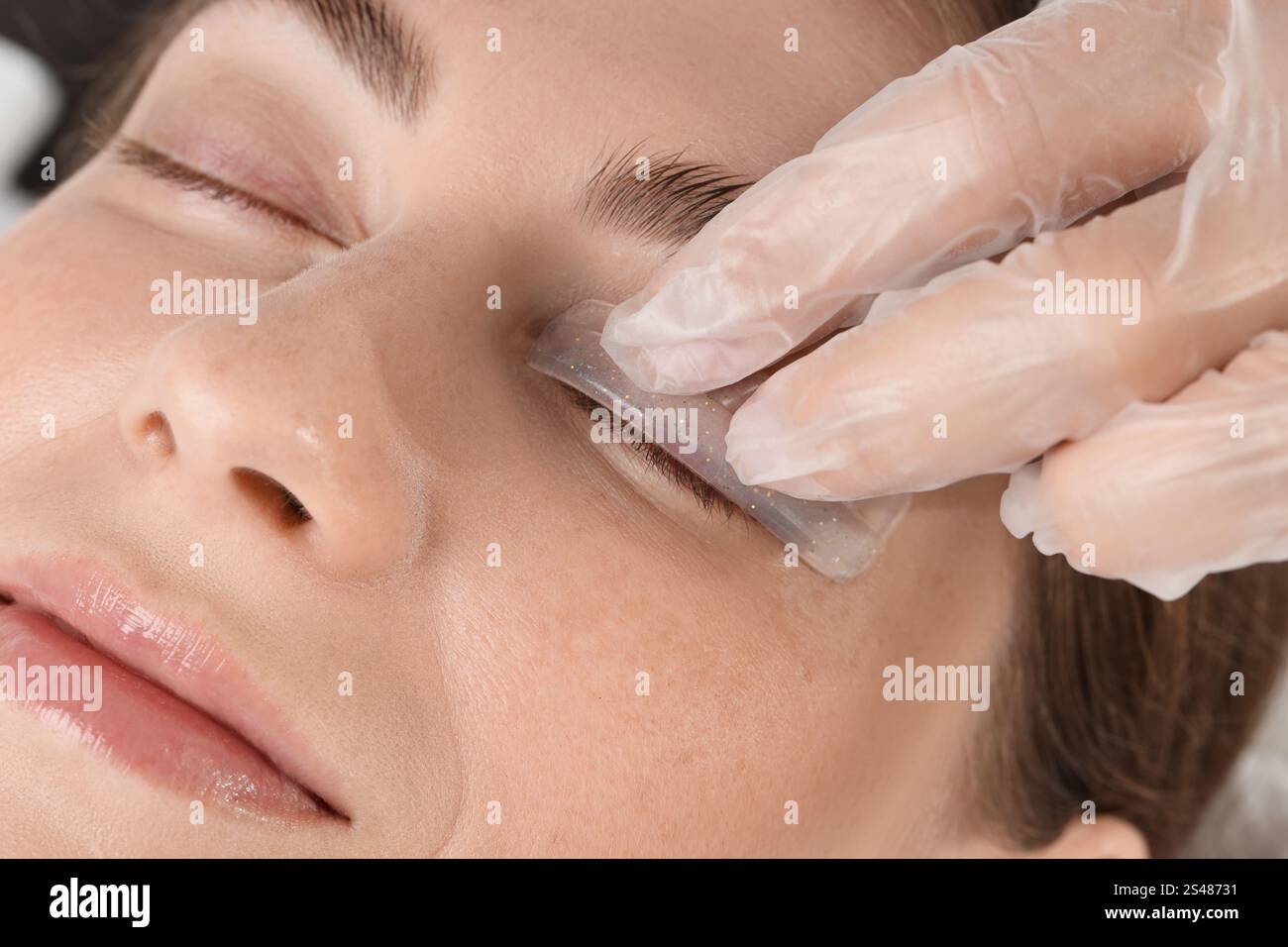 Procedura di laminazione delle ciglia. Estetista che posiziona il cuscinetto in silicone sulla palpebra della donna nel salone di bellezza, primo piano Foto Stock