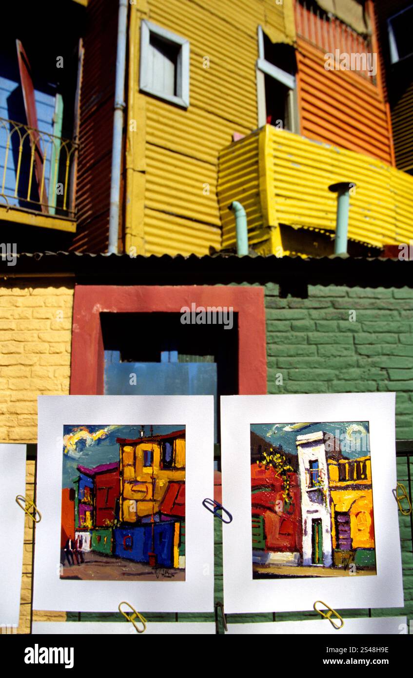 Opere d'arte in mostra a Caminito, la Boca, Buenos Aires, Argentina, sullo sfondo di colorati edifici in metallo ondulato. Foto Stock