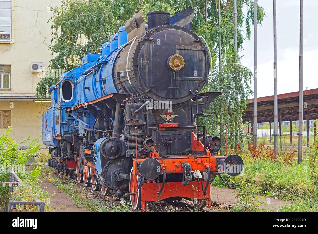 Belgrado, Serbia - 29 luglio 2019: Locomotiva a vapore del treno blu con lo stemma della storia dell'ex Jugoslavia nella stazione ferroviaria abbandonata della capitale Foto Stock