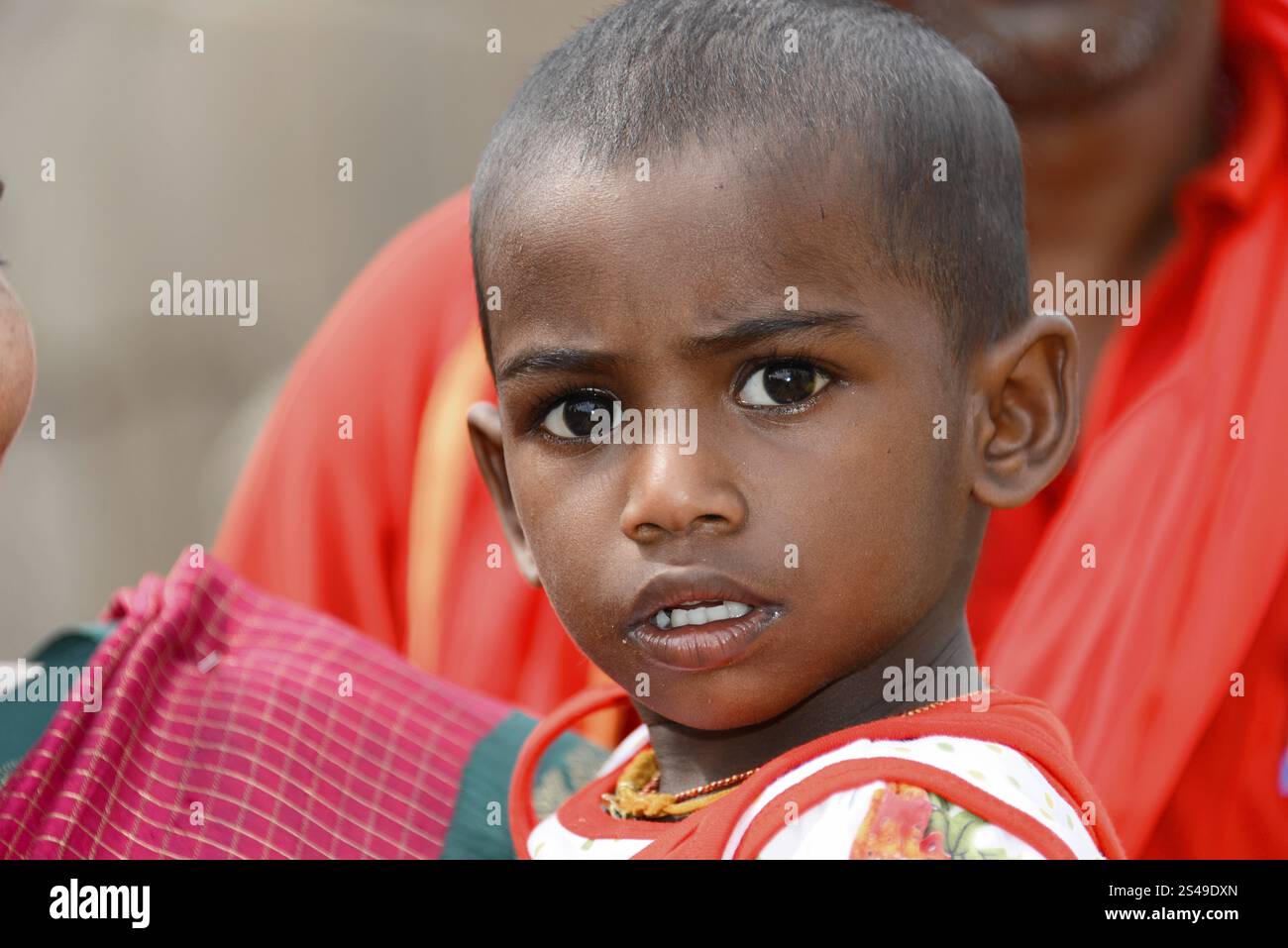 Tempio costiero di Mahabalipuram, Mamallapuram, Un bambino in abiti rossi con un'espressione curiosa e seria sul viso, Mahabalipuram, Tamil Nadu, così Foto Stock