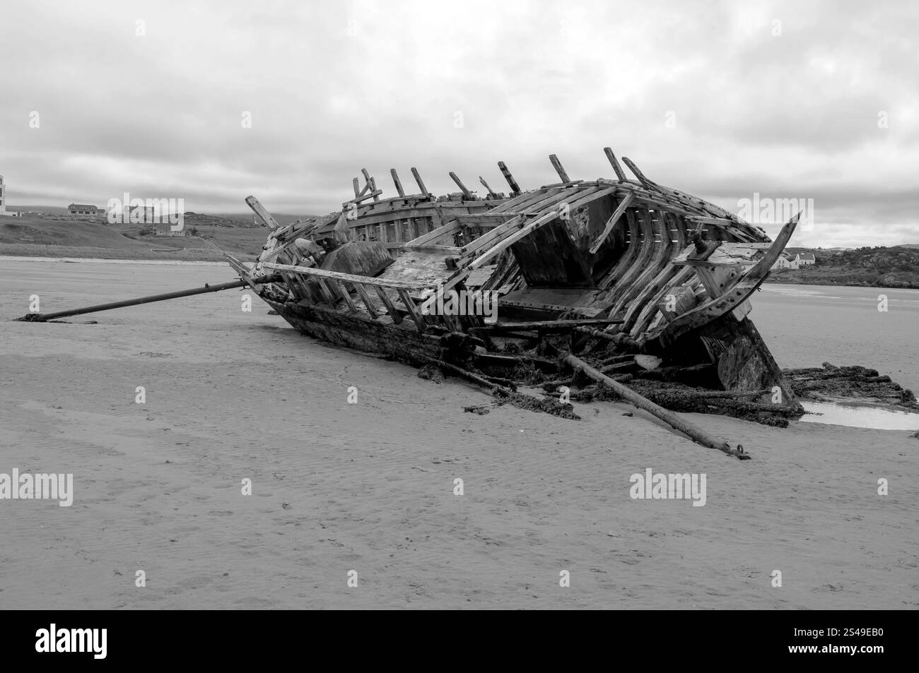 Una grande nave è adagiata sulla spiaggia, con lo scafo rotto e le vele strappate. La scena è desolata e inquietante, con i resti della nave che fungono da re Foto Stock