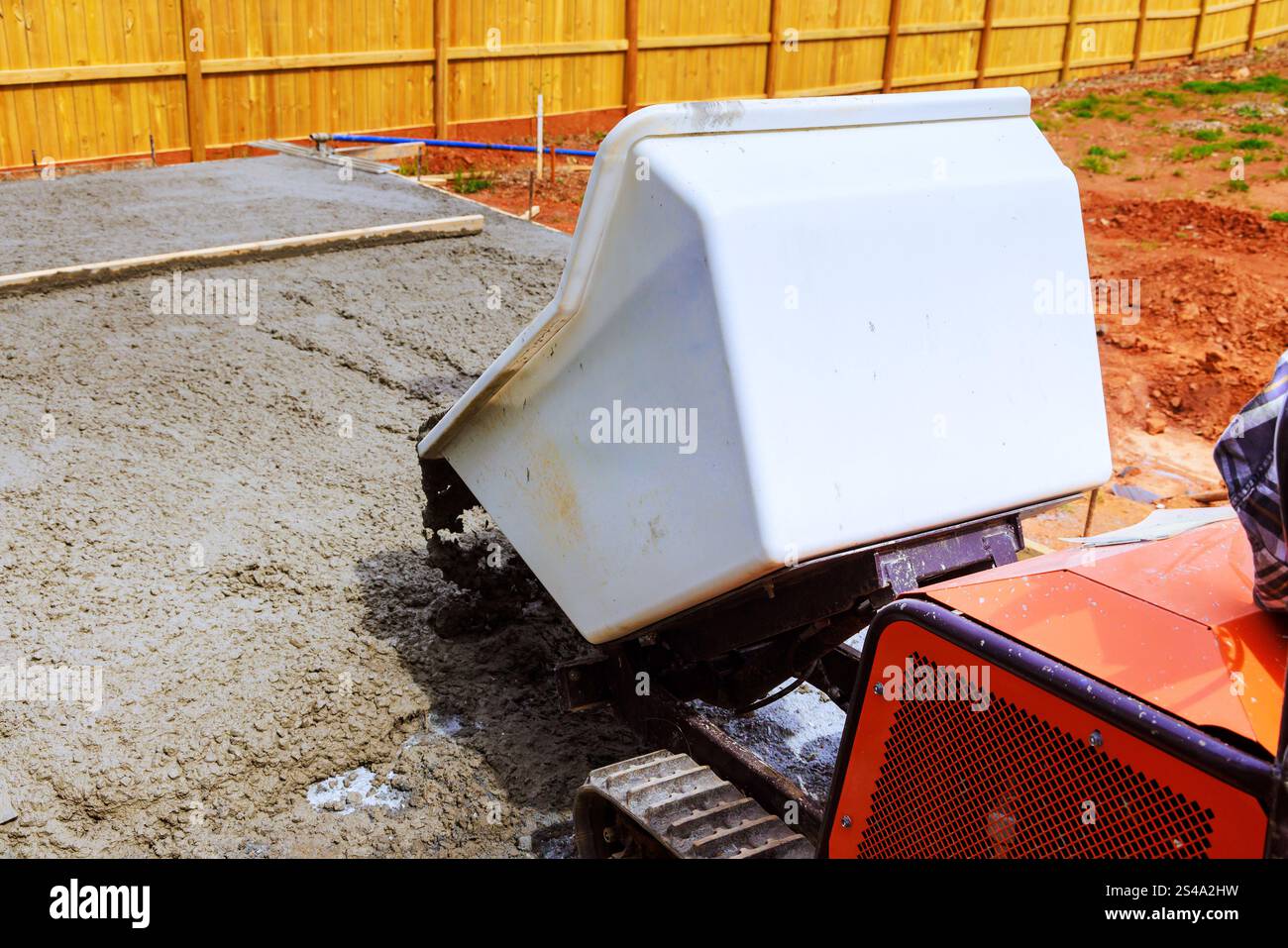 La betoniera per camion carriola versa cemento fresco nel cantiere, preparando la lastra per la nuova struttura Foto Stock