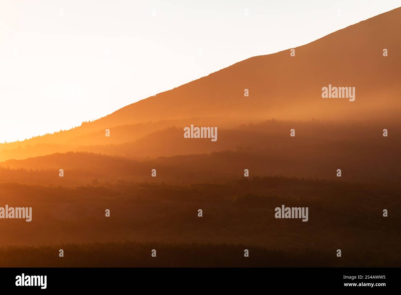 Tramonto di colore arancione brillante sulle colline ai piedi delle montagne al tramonto Foto Stock