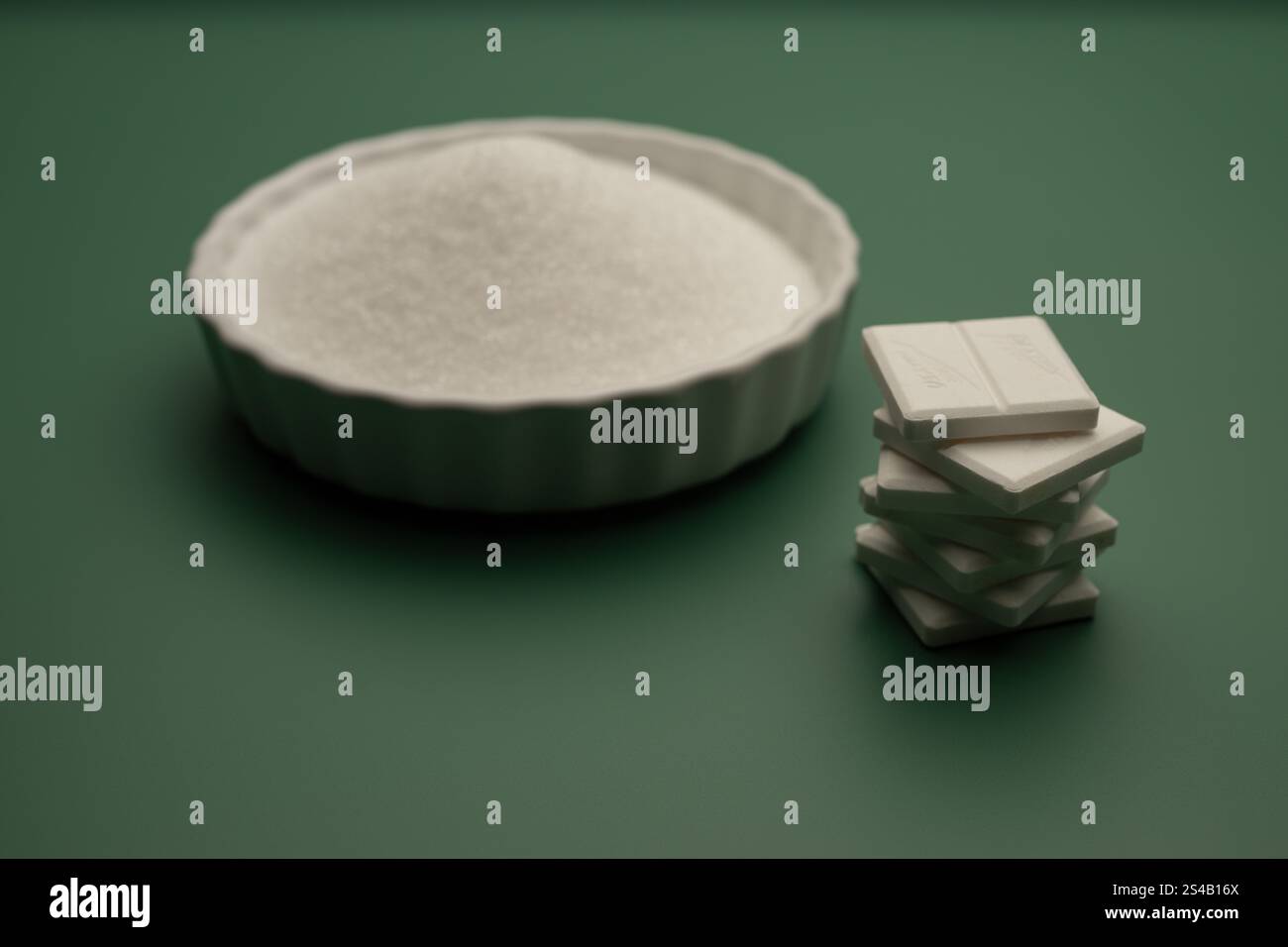 , Deutschland, 06.01.2025, Weiße Traubenzucker-Tabletten und Glycose neben einer Schale mit Erythrit auf grünem Hintergrund. Perfekt für Themen wie E. Foto Stock