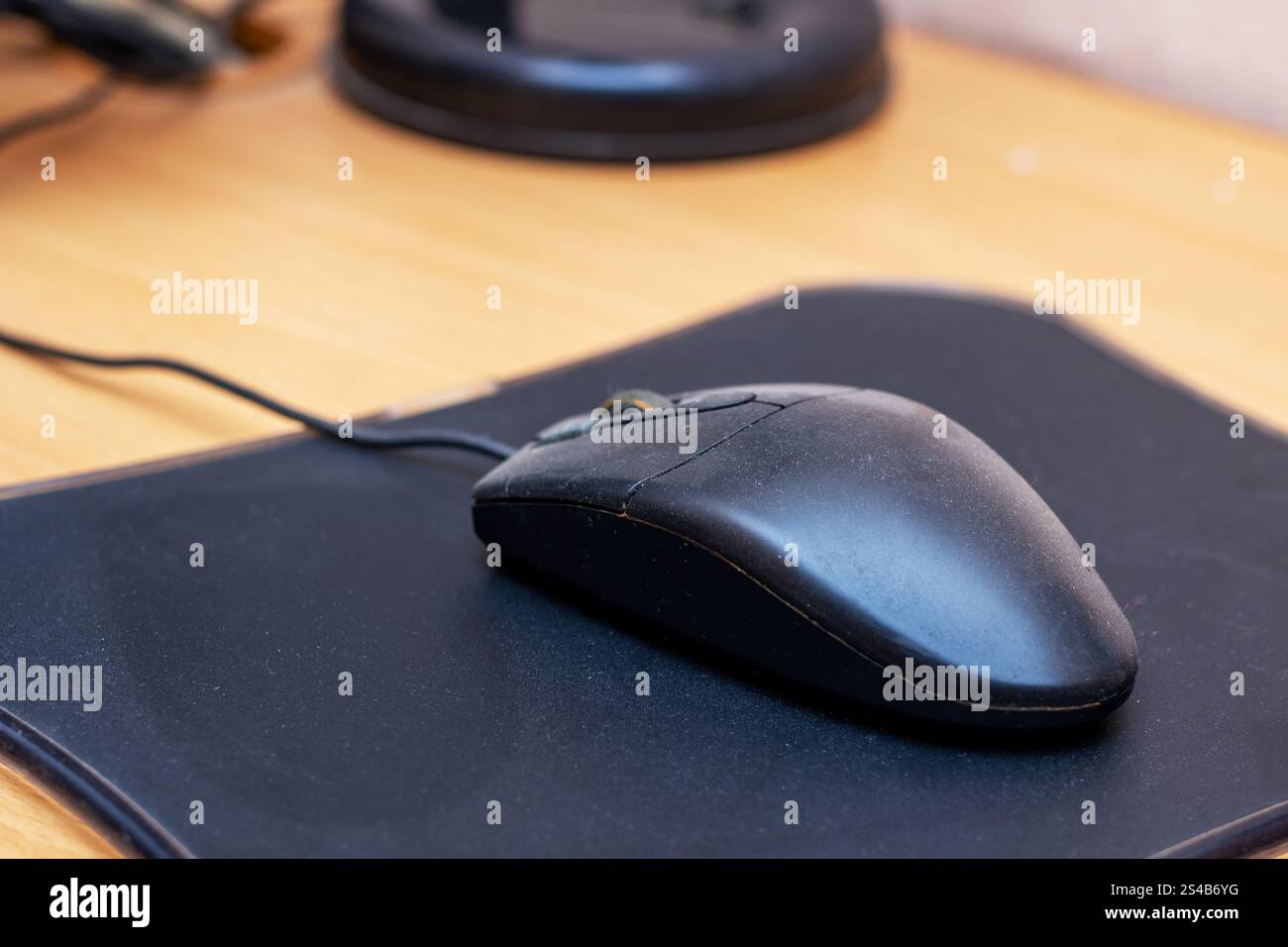 Un elegante mouse nero per computer si appoggia comodamente su un tappetino nero coordinato, creando un ambiente di lavoro compatto ed elegante Foto Stock
