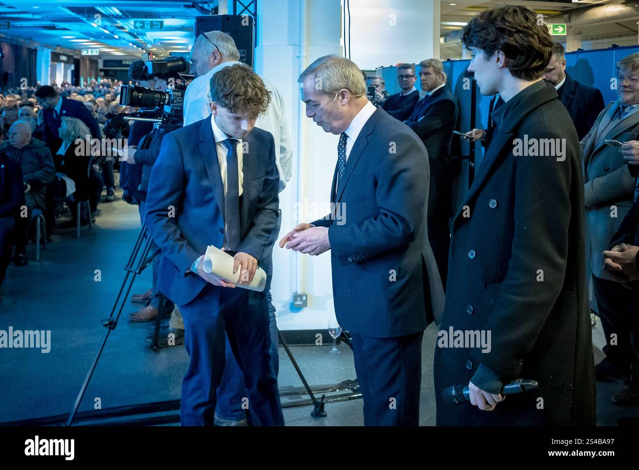 Surrey, Regno Unito. 10 gennaio 2025. Nigel Farage, leader del Reform UK, parla con Harrison Allman-Varty alla conferenza sud-est del partito al Sandown Racecourse nel Surrey, Esher. Il partito di riforma cerca di sfruttare lo slancio delle elezioni generali nel tentativo di conquistare centinaia di seggi nelle elezioni locali alla fine di quest'anno. Crediti: Guy Corbishley/Alamy Live News Foto Stock