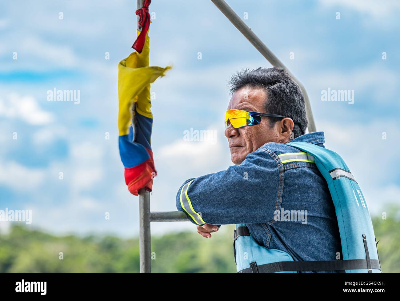 Guida turistica del Napo Wildlife Eco Lodge su una barca fluviale che indossa occhiali da sole riflettenti e giubbotto salvagente, foresta pluviale amazzonica del fiume Napo, Ecuador, Sud America Foto Stock