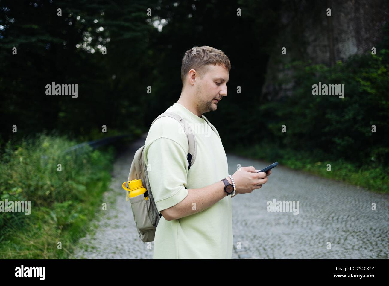Primo piano di un giovane con zaino che usa un telefono cellulare all'aperto nel parco cittadino. Foto Stock