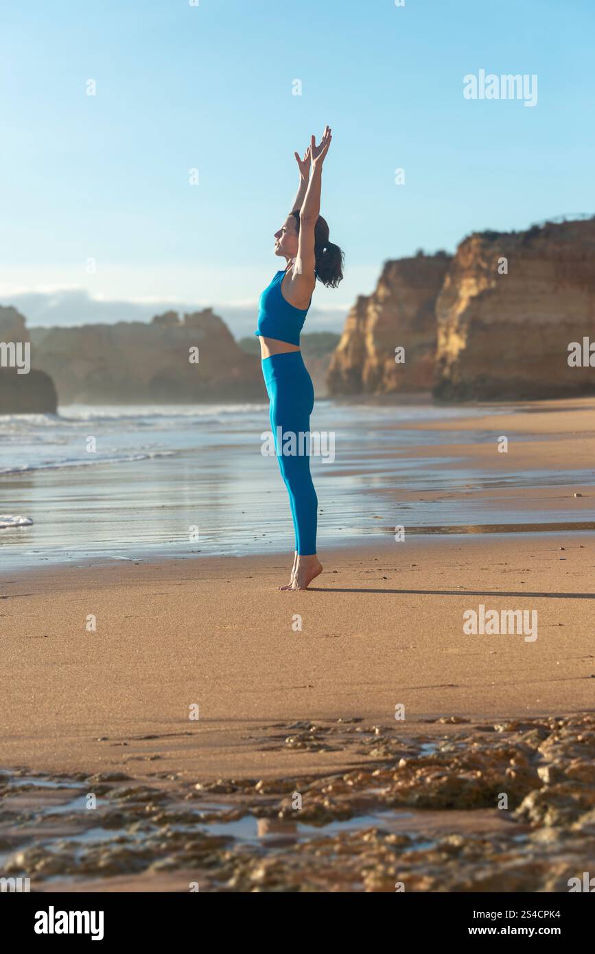donna che fa esercizi di stretching in spiaggia, mantenendosi in forma all'aperto. Foto Stock