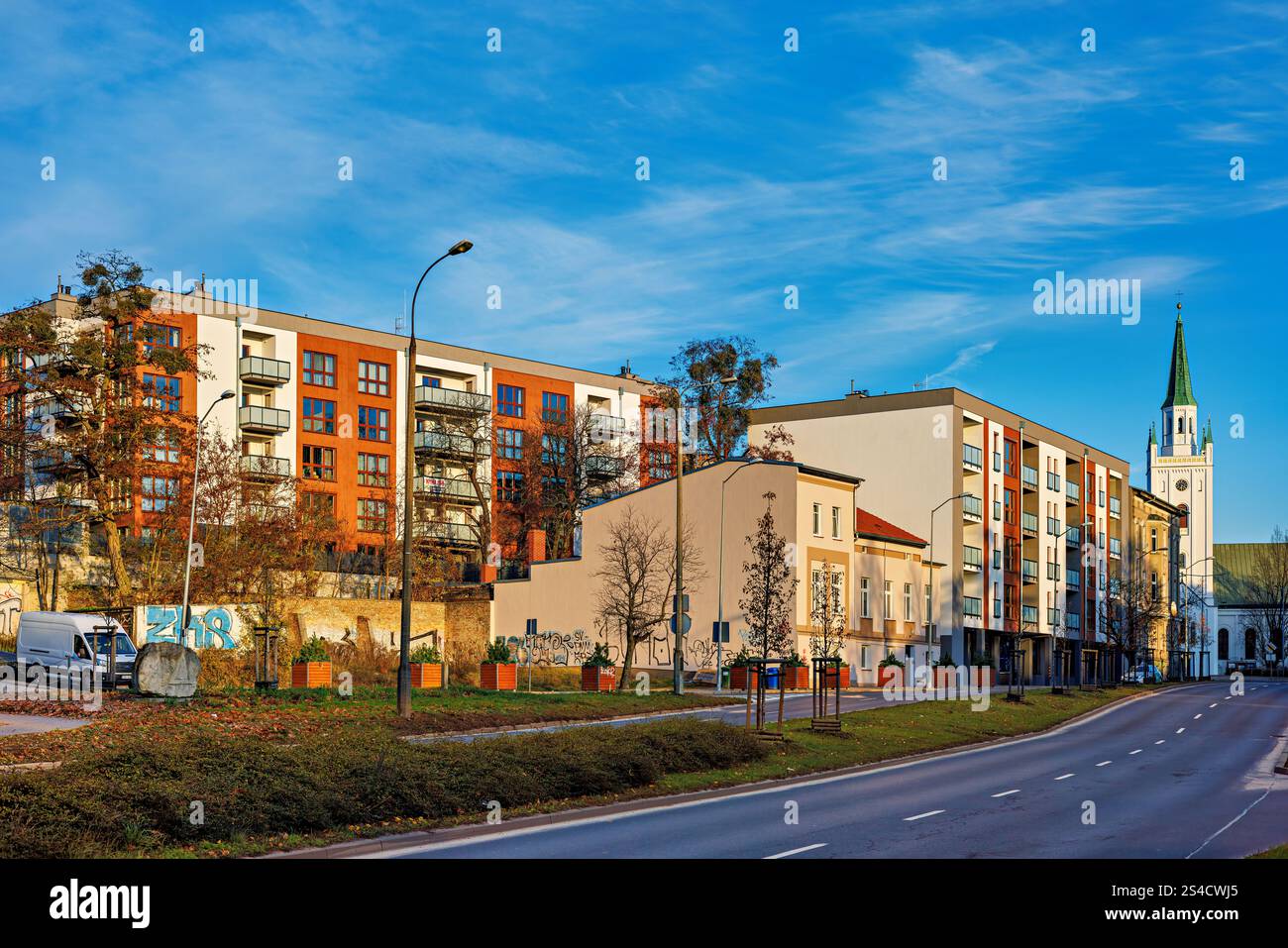 Gorzow Wielkopolski, Polonia - 30 novembre 2024: Bellissime case a pannelli e una chiesa bianca lungo la strada sullo sfondo del cielo blu. Foto Stock