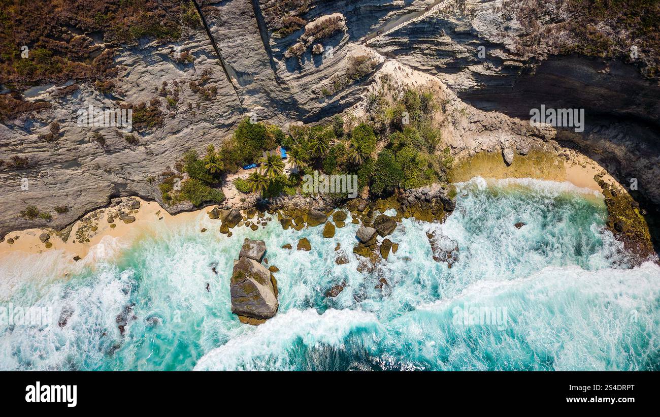 Vista a volo d'uccello delle onde dell'oceano che si infrangono contro le scogliere verticali e una piccola spiaggia Foto Stock