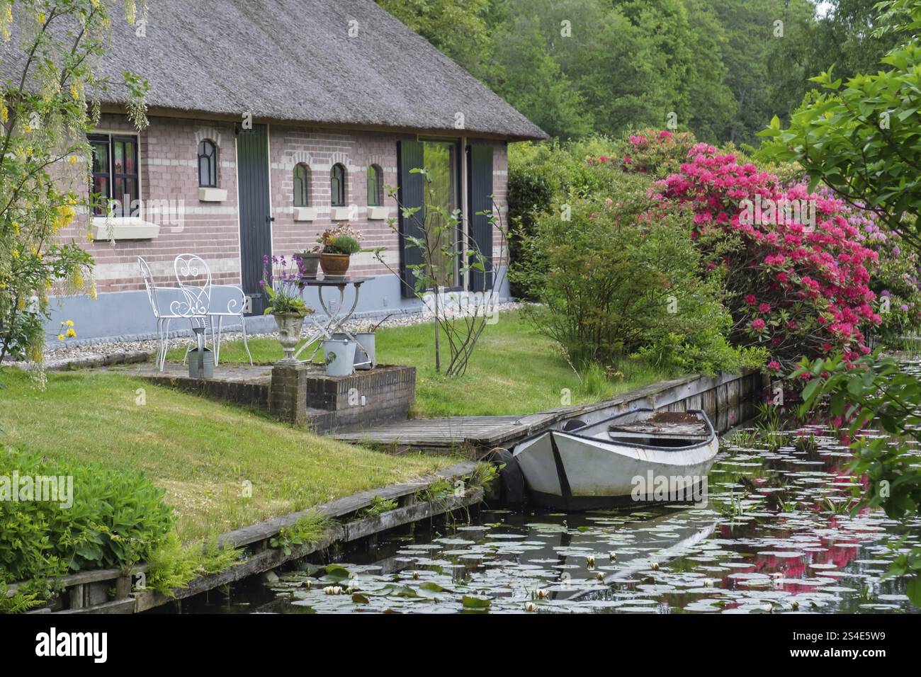 Casa accogliente sul canale con barca e arbusti fioriti in una zona idilliaca, Giethoorn, comune di Steenwijkerland, provincia di Overijssel, Netherl Foto Stock