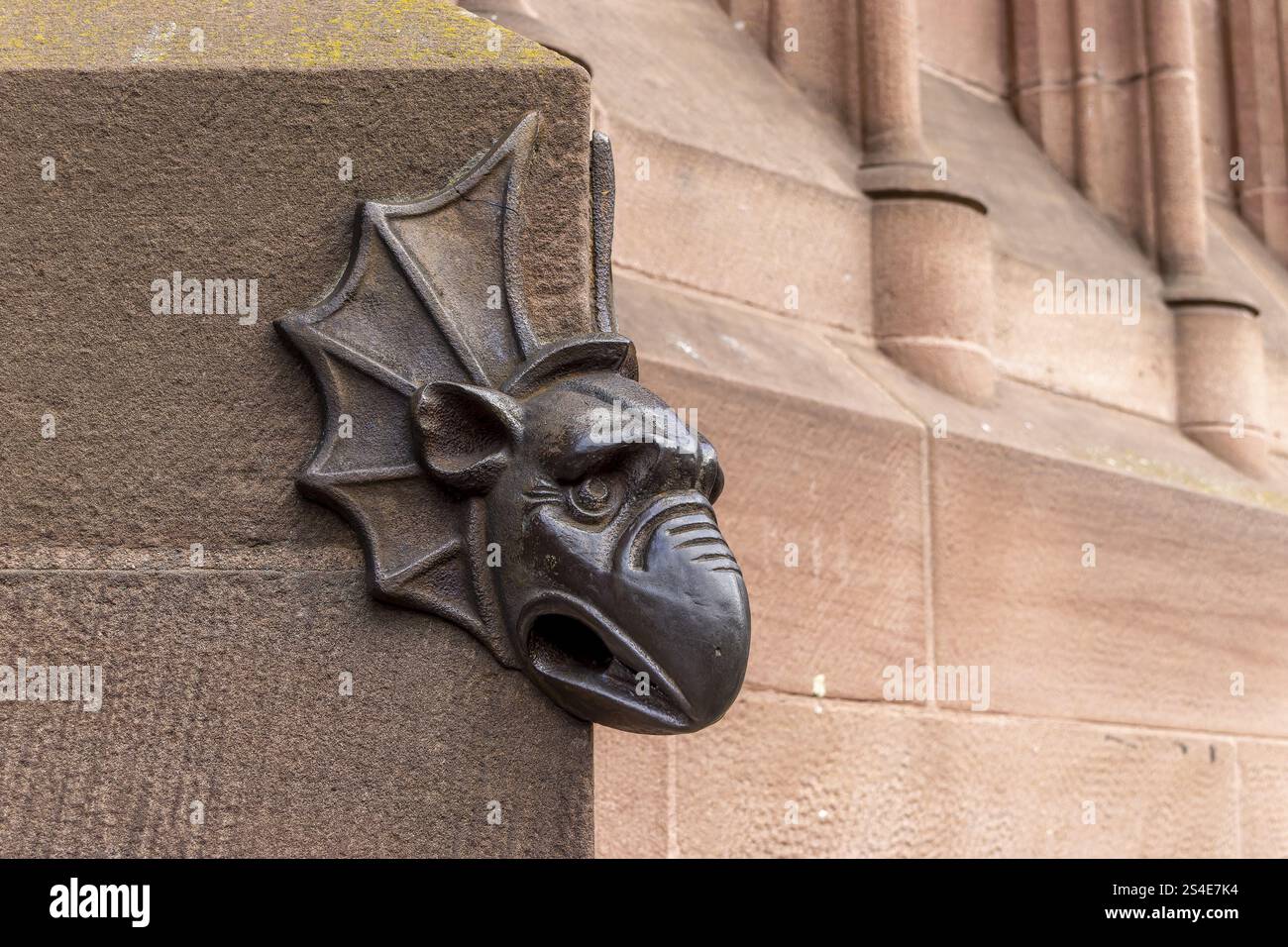 La testa di ferro di una creatura immaginaria all'angolo dell'edificio, accanto all'ingresso principale del portale principale alto gotico della cattedrale di Strasburgo Foto Stock