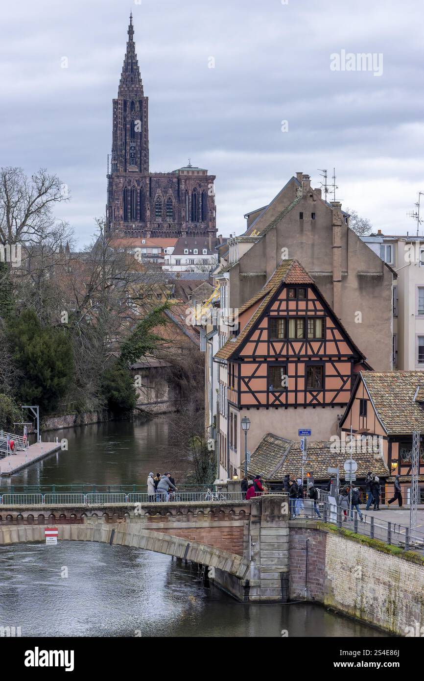 Ponte medievale Ponts Couverts de Strasbourg sul fiume Ill e su una casa marrone a graticcio e sullo sfondo l'imponente edificio dell'Hig Foto Stock