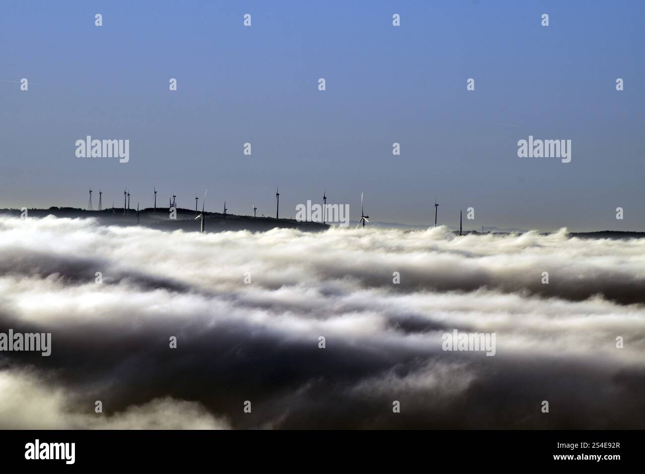 Vista dal Wildenburger Kopf nel Parco Nazionale Hunsrueck-Hochwald della regione di Nahe con turbine eoliche in una nebbiosa mattina d'inverno, Rhineland-Pal Foto Stock