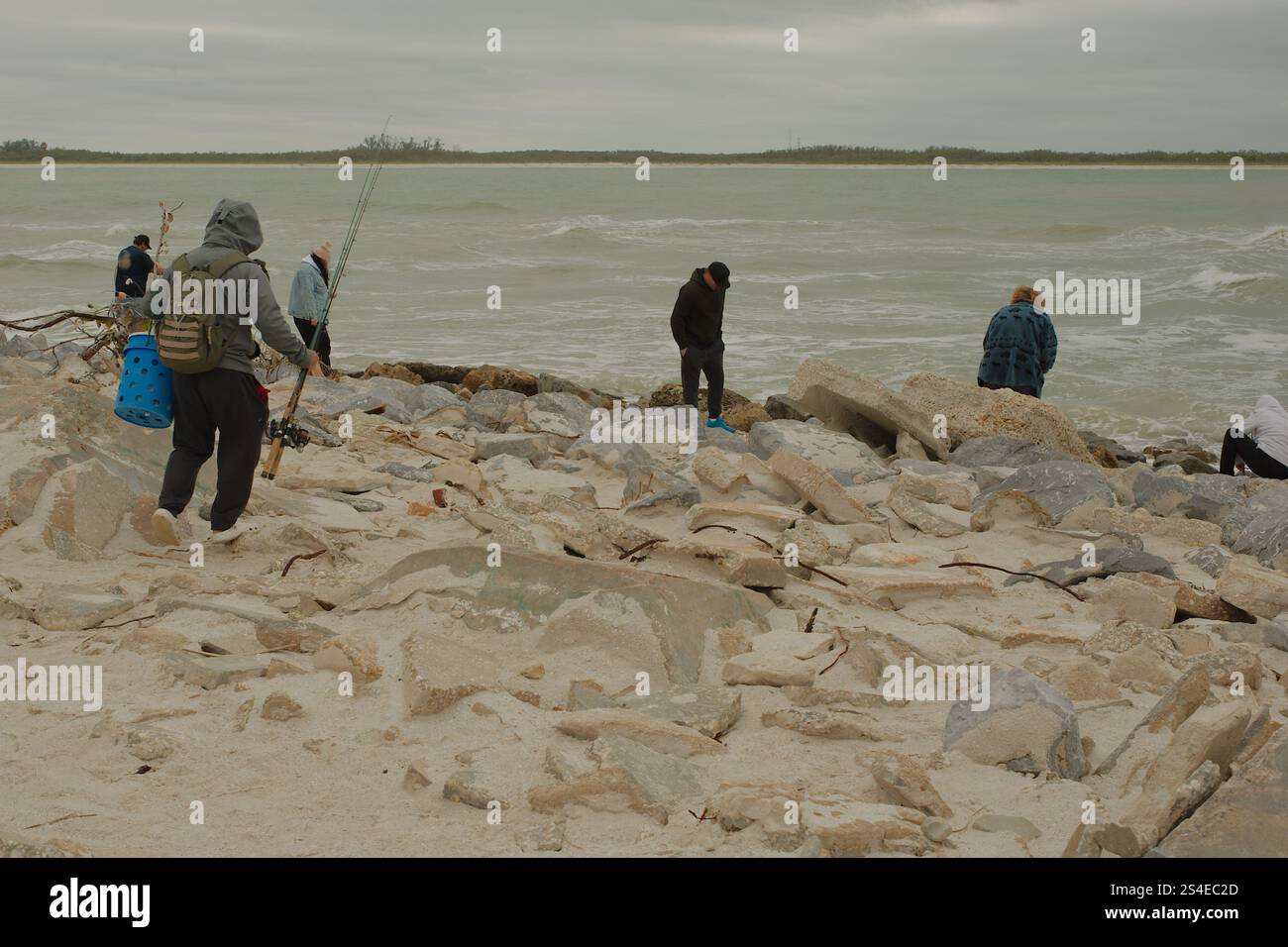 St. Pete Beach, Florida, Pass-a-Grille Beach Vista a sud su grandi rocce, molte persone verso Shell Key Island. Nel tardo pomeriggio, nuvoloso. Foto Stock
