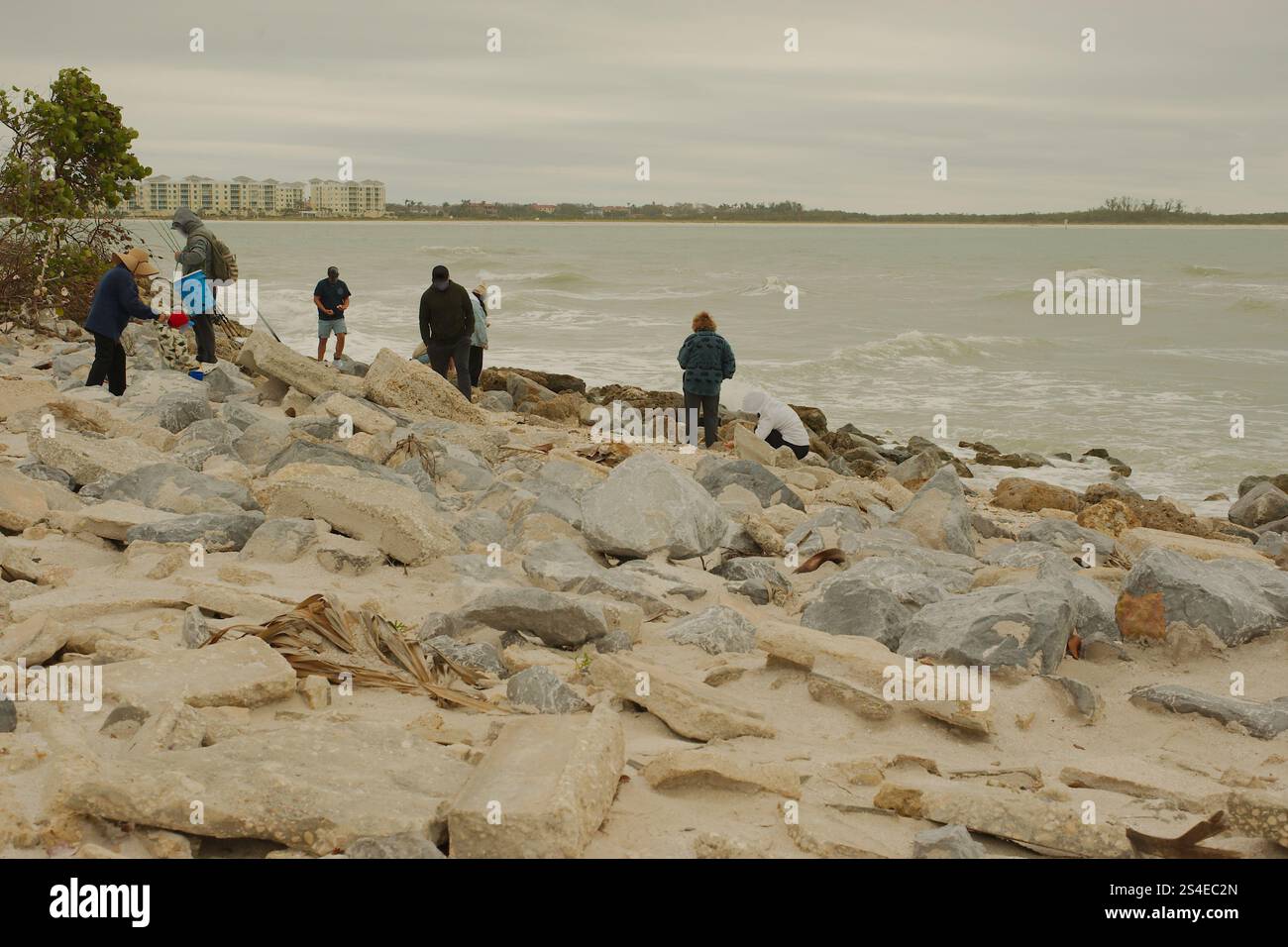 St. Pete Beach, Florida, Pass-a-Grille Beach Vista a sud su grandi rocce, molte persone verso Shell Key Island. Nel tardo pomeriggio, nuvoloso. Foto Stock