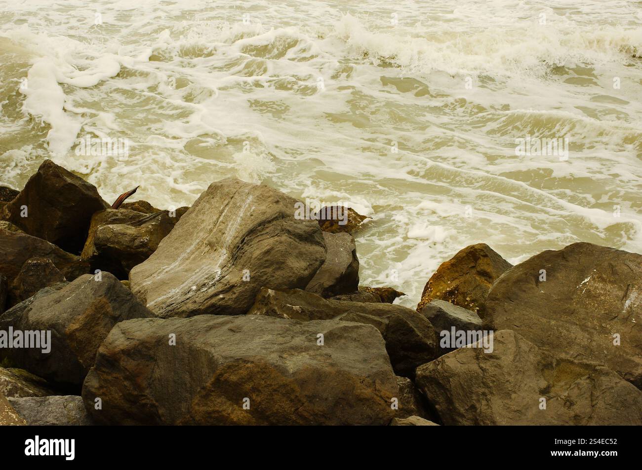 Ammira le grandi rocce di St. Pete Beach, Florida, Pass-a-Grille. Grandi onde bianche che si tuffano su e sopra grandi rocce. In una giornata nuvolosa. Roo Foto Stock