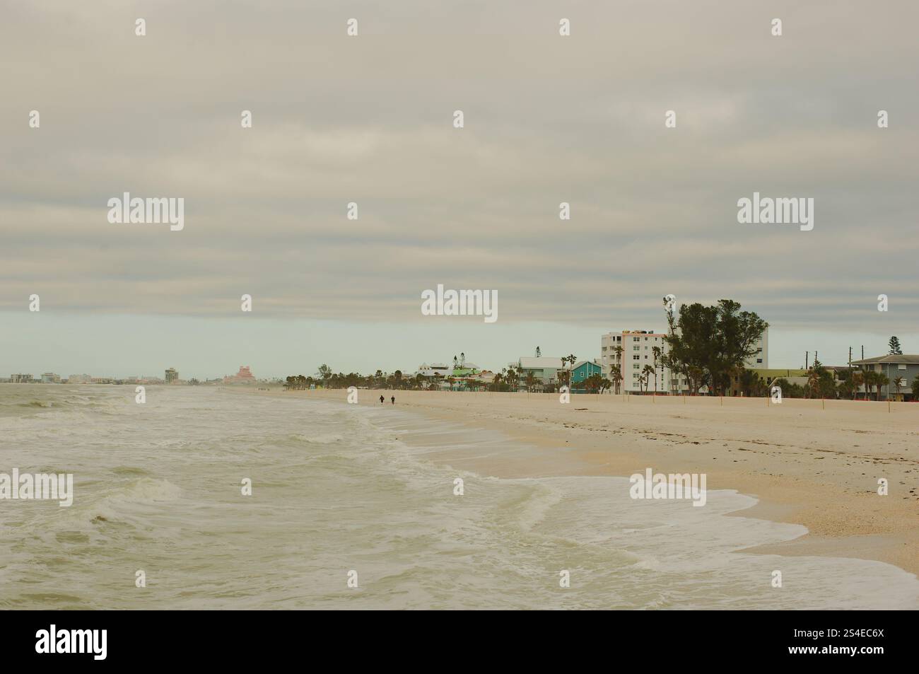 Ampia vista a nord sulla sabbia e sulle onde in una giornata nuvolosa con gli hotel a poca distanza. St. Pete Beach, Florida, spiaggia Pass-a-Grille sul Golfo del Messico. G Foto Stock