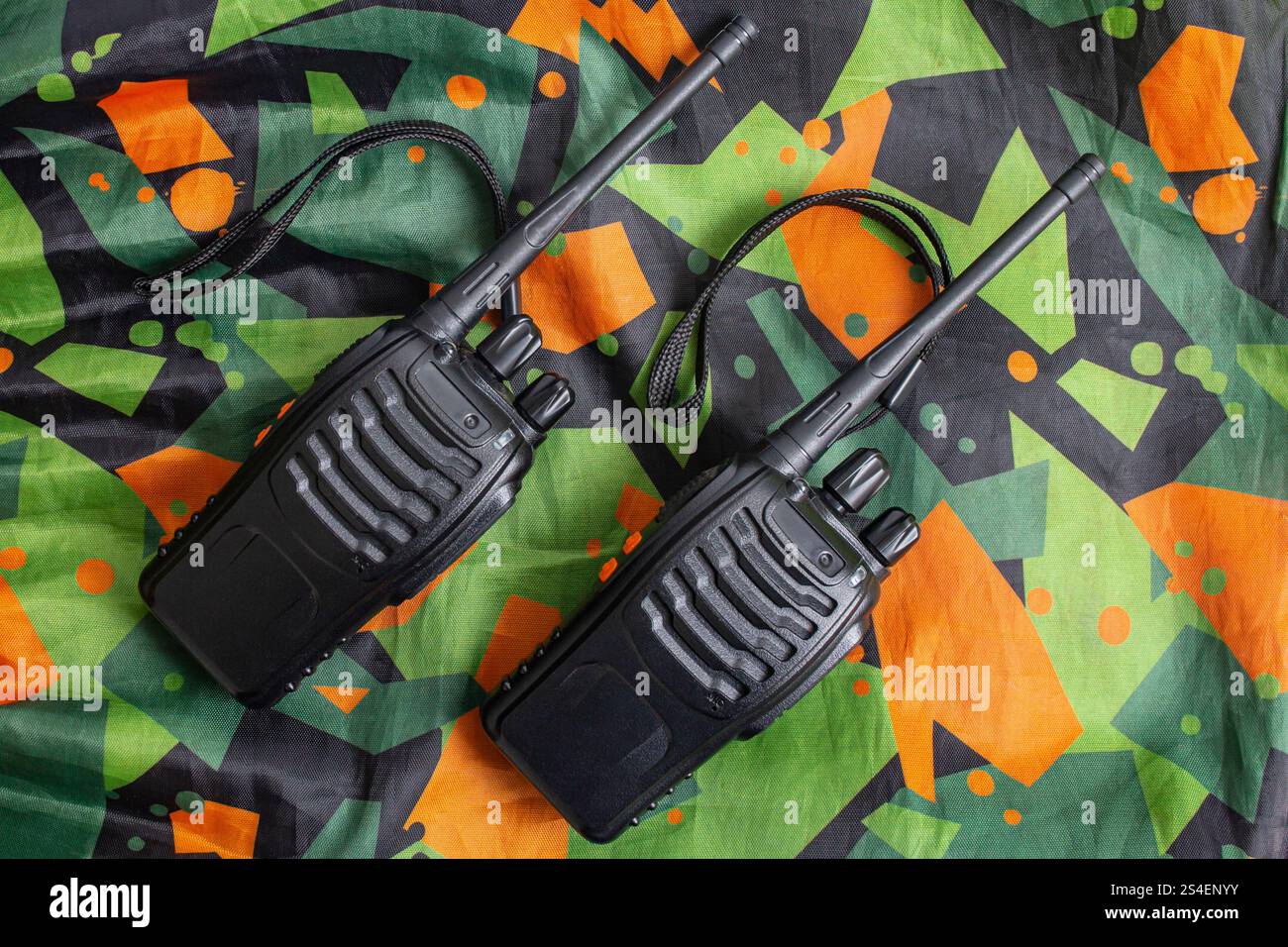 due walkie talkie in tessuto mimetico con motivo verde e arancione, con disposizione piatta Foto Stock