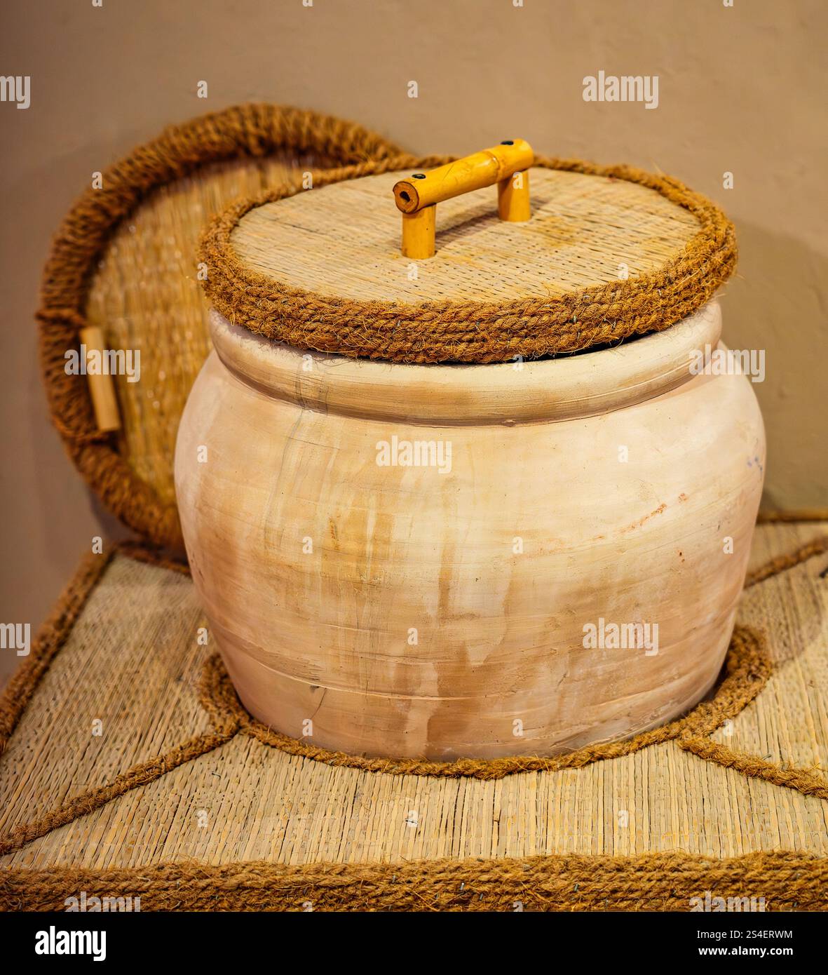 Un tradizionale vaso di terracotta dell'Oman con coperchio in corda e manico in bambù, che mostra intricate lavorazioni artigianali, patrimonio culturale e tradizionale storag Foto Stock