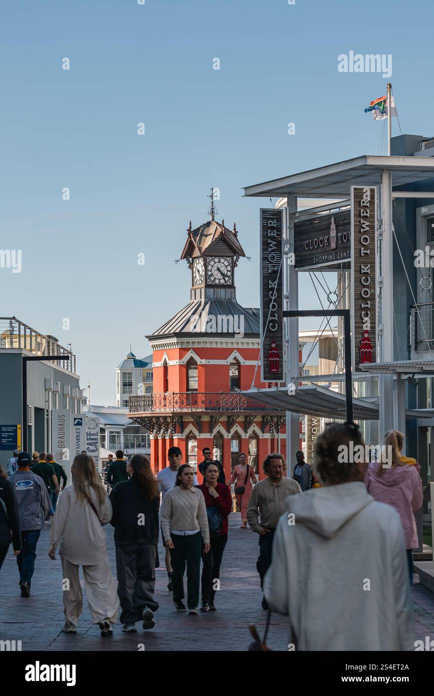 Le persone camminano vicino a un monumento storico della città, il lungomare della Torre dell'Orologio. La strada serale prima del tramonto è piena di turisti. Città del Capo, Sou Foto Stock