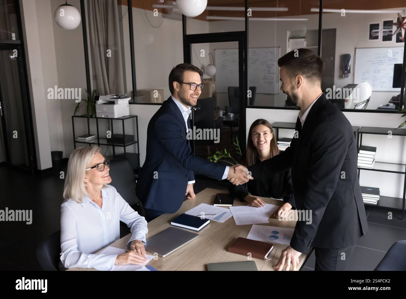 Gruppo di azionisti che si salutano prima delle negoziazioni in sala riunioni Foto Stock