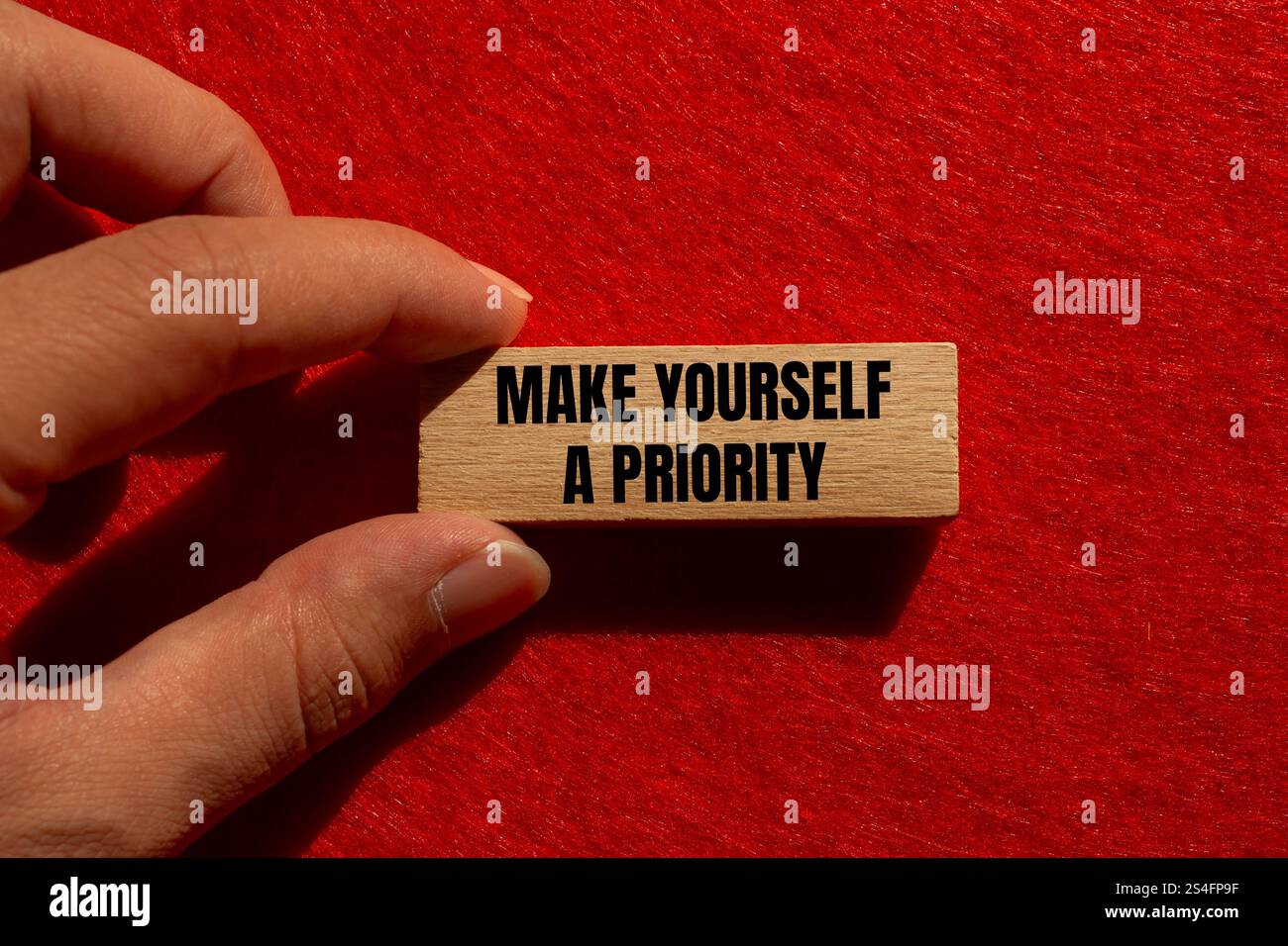 Fatevi un messaggio prioritario scritto su un blocco di legno con sfondo rosso. Concettuale, diventa un simbolo di priorità. Copia spazio. Foto Stock