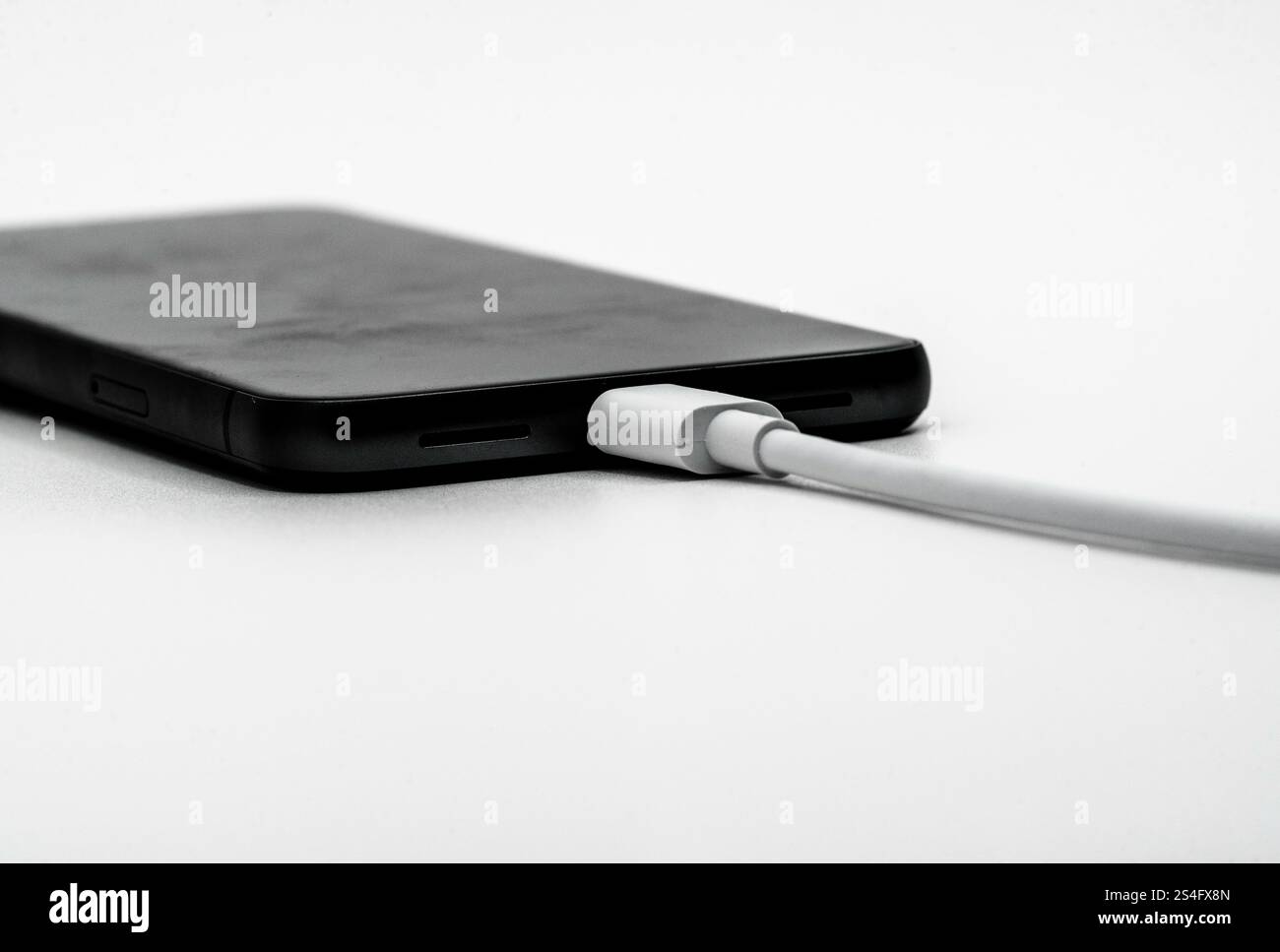 un telefono cellulare e un cavo di ricarica Foto Stock