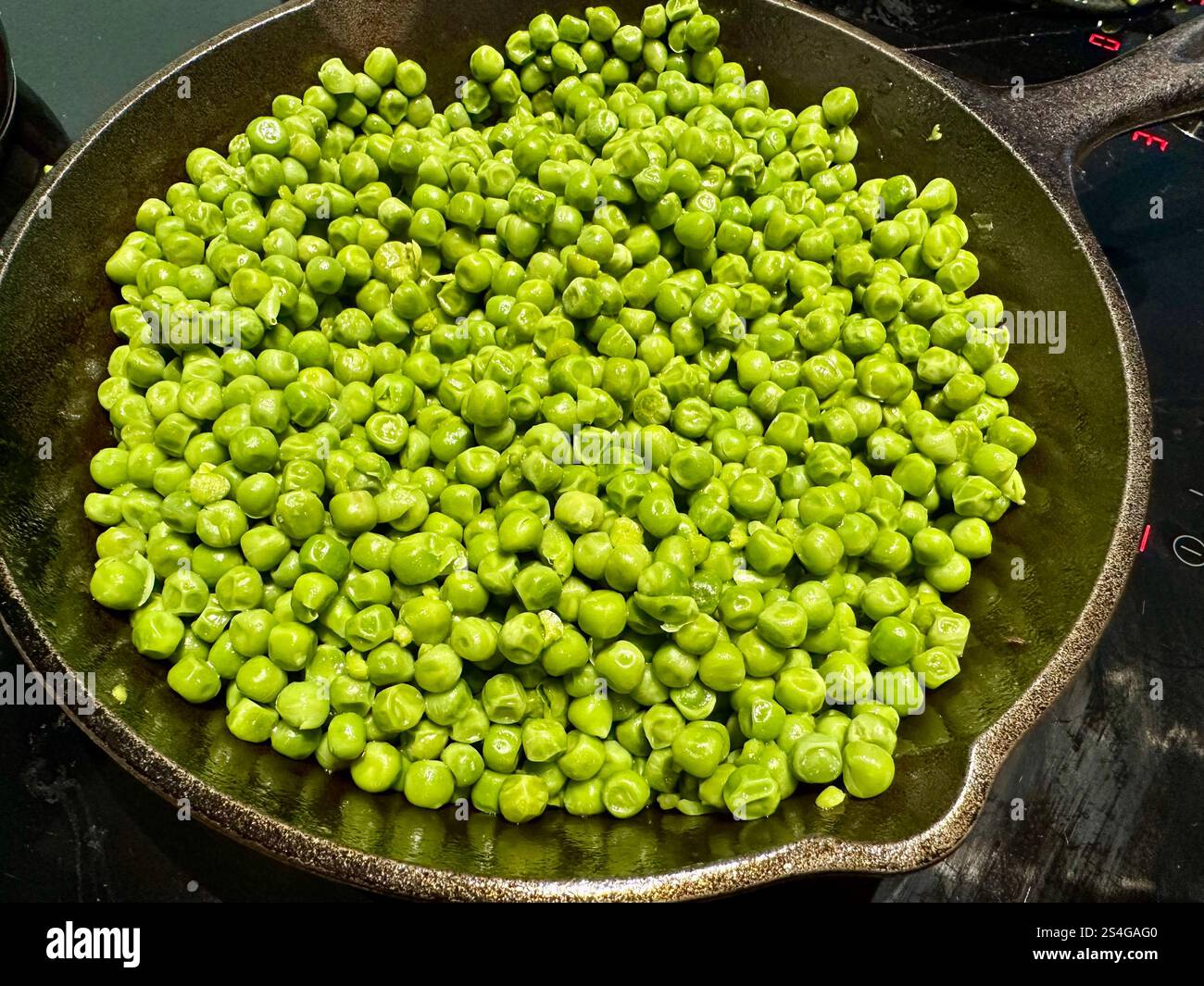 Piselli verdi in una padella di ghisa - Immagine stock catturata con smartphone