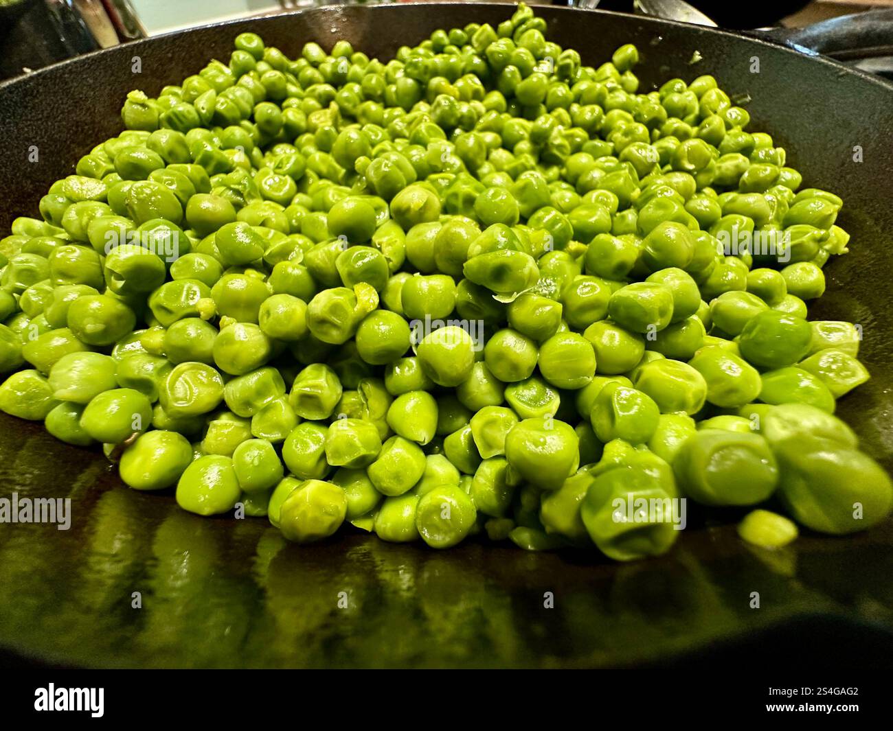 Piselli verdi in una padella di ghisa - Immagine stock catturata con smartphone