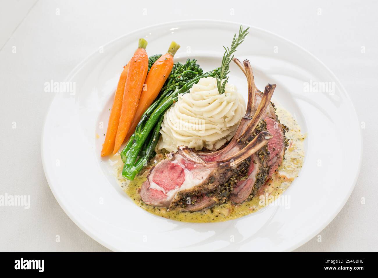 Un piatto di costolette di agnello, patate e carote. Le costolette di agnello vengono tagliate a pezzi e servite con un lato di purè di patate e carote al vapore. TH Foto Stock