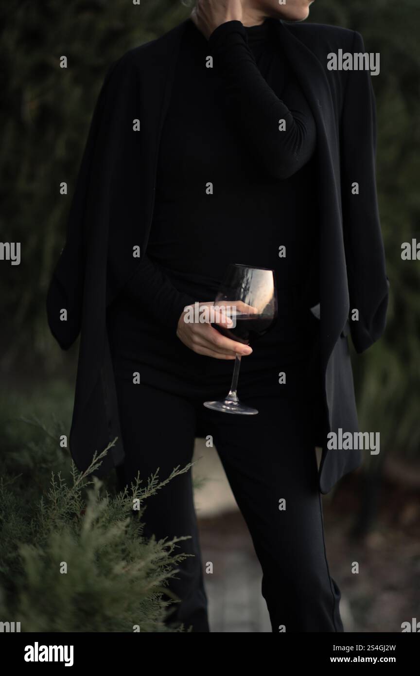 Ragazza con un bicchiere di vite a una festa sul retro in abito nero Foto Stock