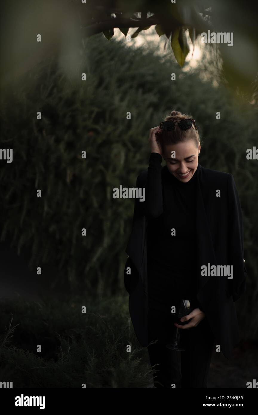 Ragazza con un bicchiere di vite a una festa sul retro in abito nero Foto Stock